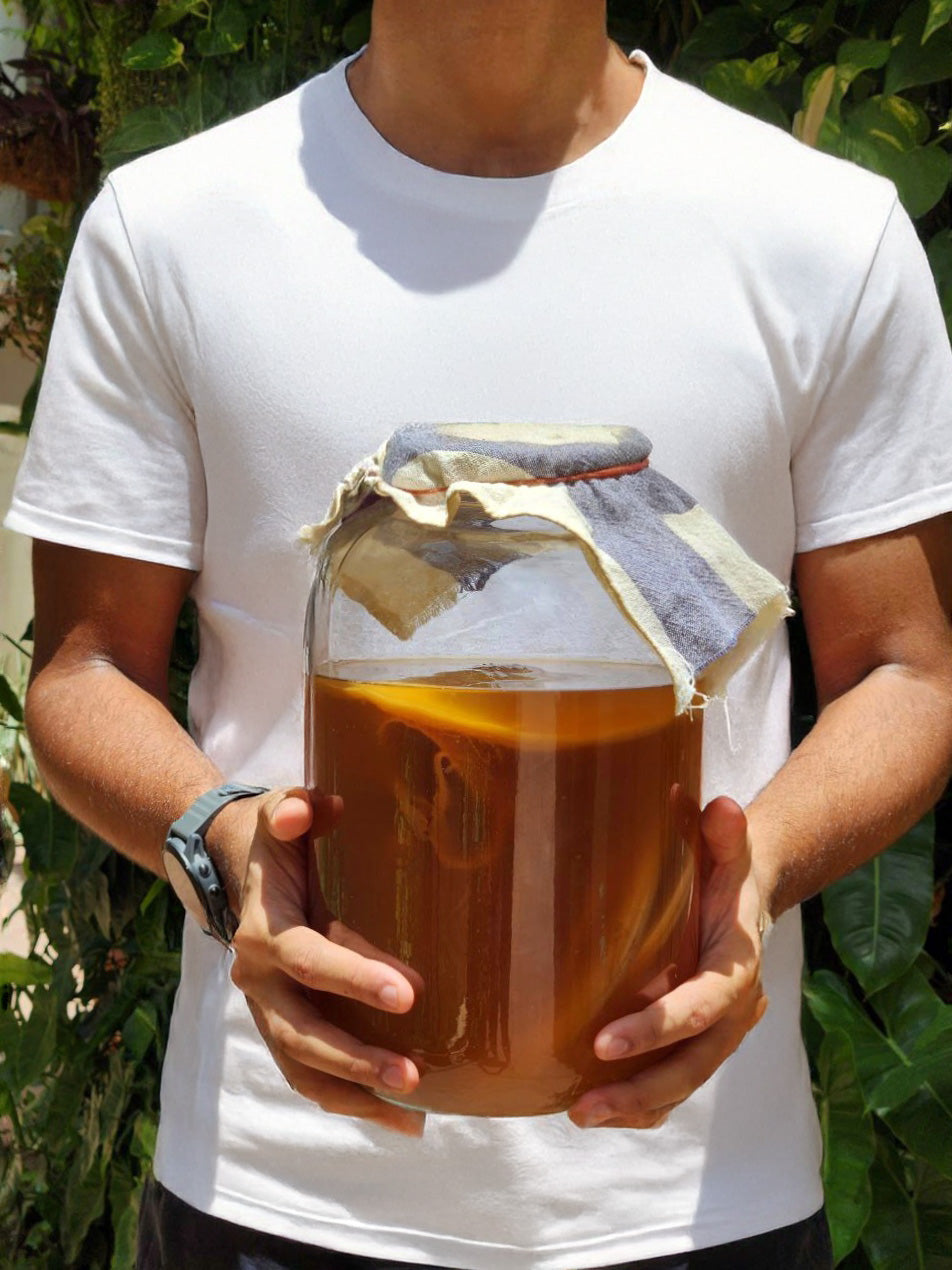 A man holding a scoby jar & kombucha